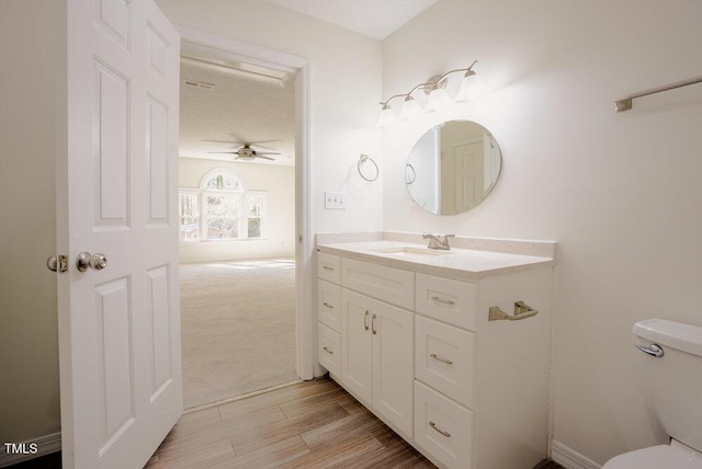 bathroom featuring toilet, wood finished floors, a textured ceiling, and vanity