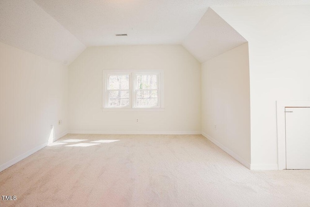 additional living space featuring lofted ceiling, light carpet, and visible vents