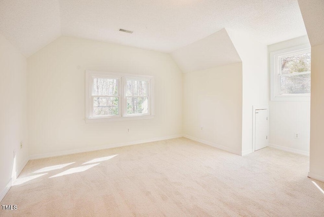 bonus room featuring lofted ceiling, plenty of natural light, visible vents, and a textured ceiling