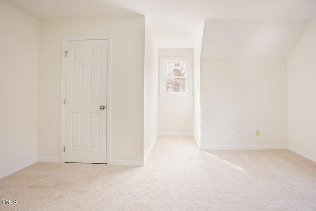 carpeted spare room featuring a textured ceiling and baseboards