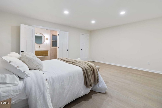 bedroom with ensuite bath, light wood-style flooring, baseboards, and recessed lighting