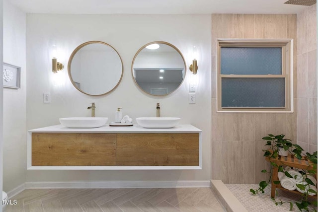 full bathroom featuring double vanity, a sink, baseboards, and walk in shower