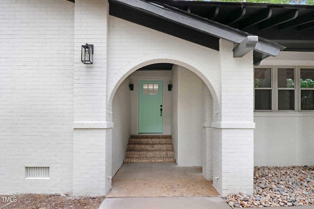 property entrance featuring brick siding and crawl space