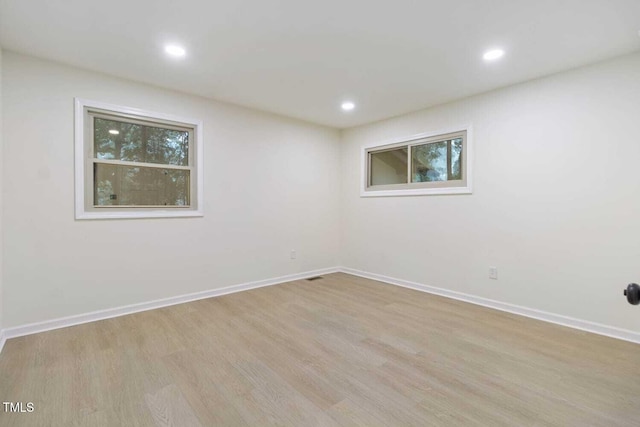 spare room with baseboards, wood finished floors, and recessed lighting