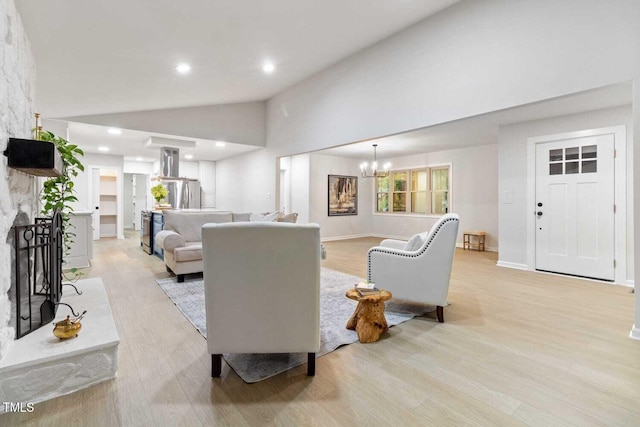 living area with light wood-type flooring, a large fireplace, recessed lighting, and an inviting chandelier