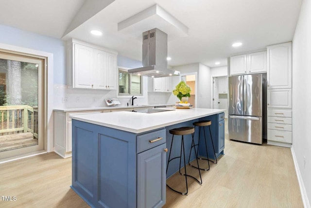 kitchen featuring a center island, light wood-style floors, freestanding refrigerator, white cabinets, and island range hood