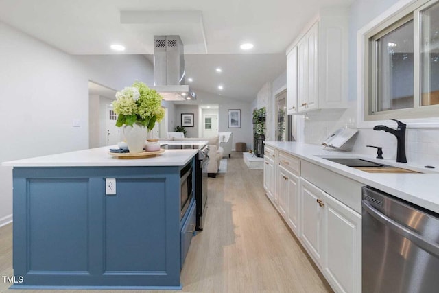 kitchen with appliances with stainless steel finishes, white cabinets, a sink, and exhaust hood