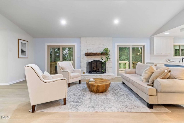 living area featuring recessed lighting, a fireplace, baseboards, vaulted ceiling, and light wood-type flooring