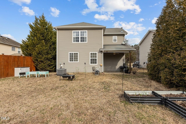 back of property featuring fence, a vegetable garden, cooling unit, and a yard