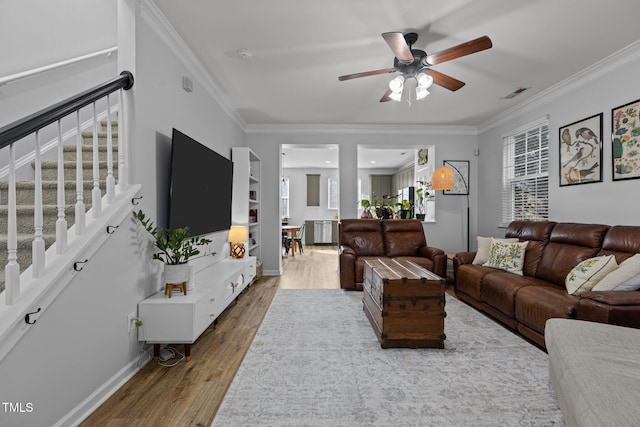 living room with crown molding, stairs, visible vents, and wood finished floors