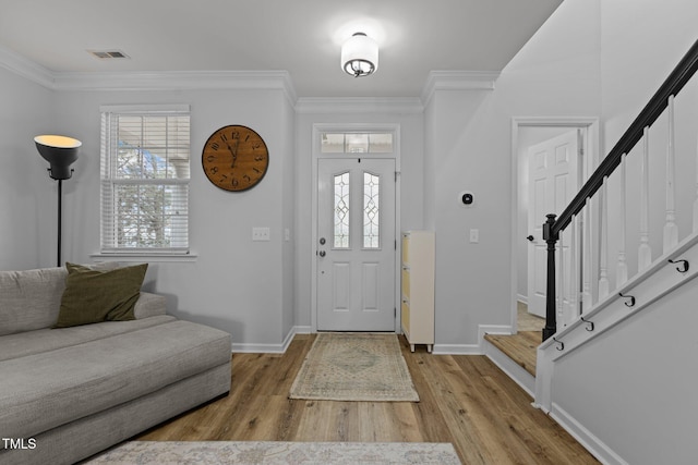 entrance foyer featuring stairs, ornamental molding, light wood finished floors, and visible vents