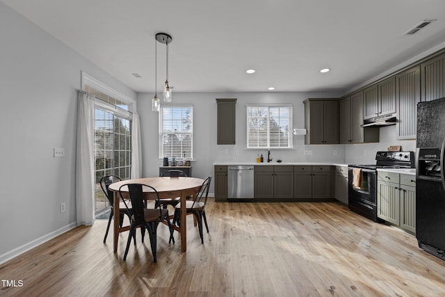 kitchen with light wood-style flooring, under cabinet range hood, visible vents, light countertops, and black appliances