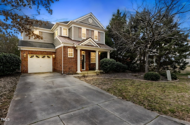 traditional-style house with a garage, concrete driveway, brick siding, and covered porch