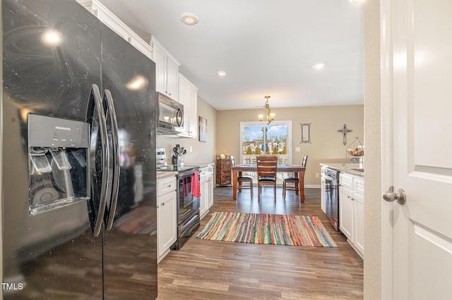 kitchen featuring pendant lighting, wood finished floors, white cabinets, light stone countertops, and black appliances