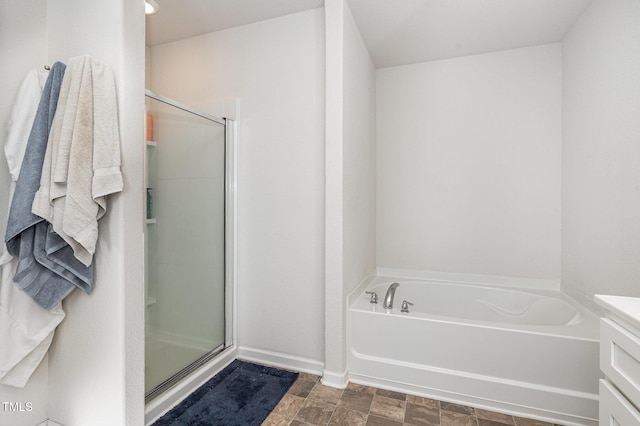 full bathroom with stone finish floor, a shower stall, a bath, and baseboards