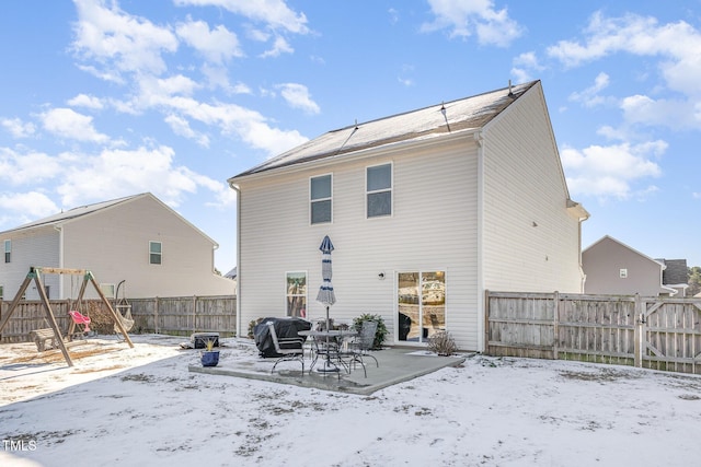 snow covered property with a playground, a patio, and a fenced backyard