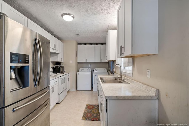 kitchen featuring washing machine and dryer, a sink, light countertops, stainless steel fridge, and white electric range oven