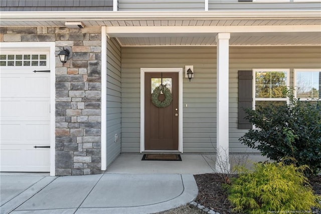 entrance to property featuring stone siding, a porch, and an attached garage