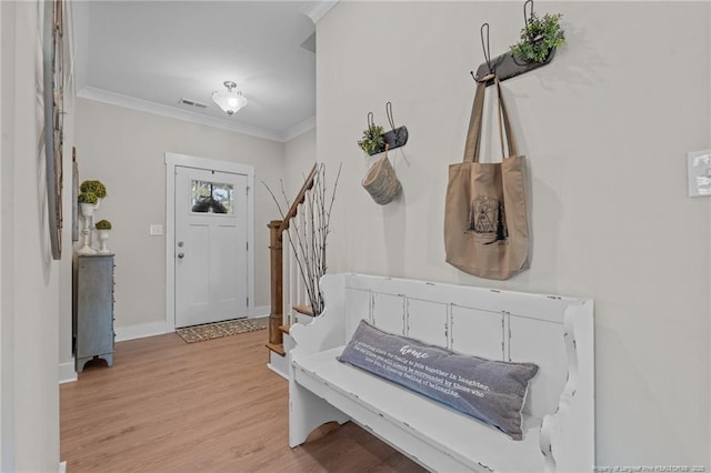 entrance foyer with visible vents, stairway, light wood-style flooring, ornamental molding, and baseboards