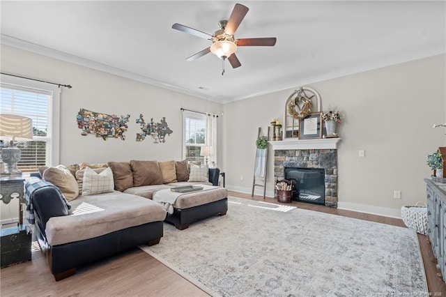 living area with a fireplace, crown molding, baseboards, and wood finished floors