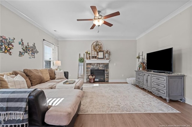 living room with baseboards, a ceiling fan, ornamental molding, wood finished floors, and a fireplace