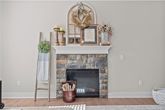 room details featuring baseboards, wood finished floors, and a stone fireplace