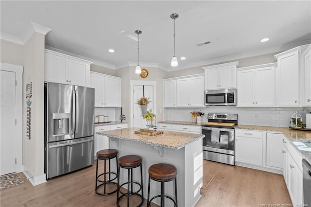 kitchen with stainless steel appliances, a center island, white cabinets, and light wood finished floors