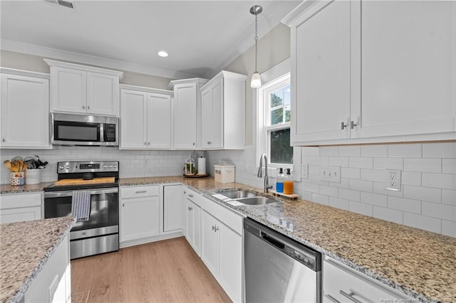 kitchen with a sink, white cabinetry, light wood-style floors, appliances with stainless steel finishes, and tasteful backsplash