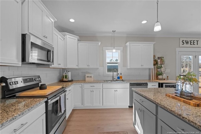 kitchen featuring stainless steel appliances, a sink, white cabinets, and a healthy amount of sunlight