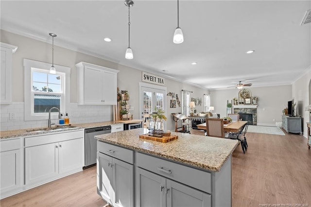 kitchen with a sink, a fireplace, decorative backsplash, and dishwasher