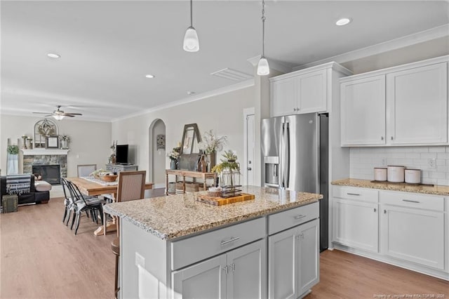 kitchen with light wood-type flooring, crown molding, arched walkways, and backsplash