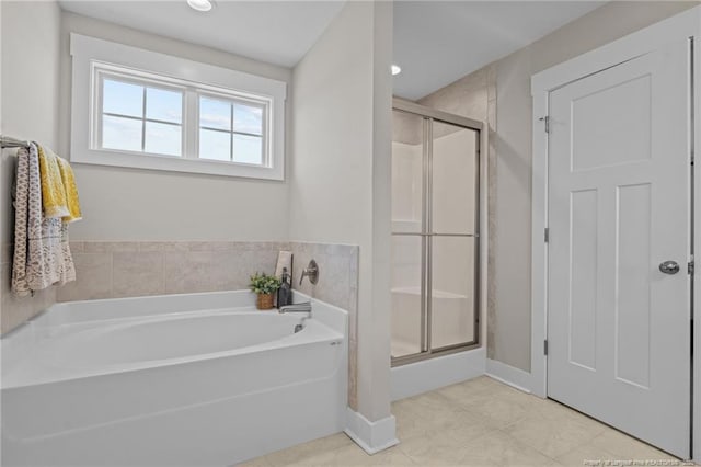 full bathroom with a stall shower, baseboards, a bath, and tile patterned floors