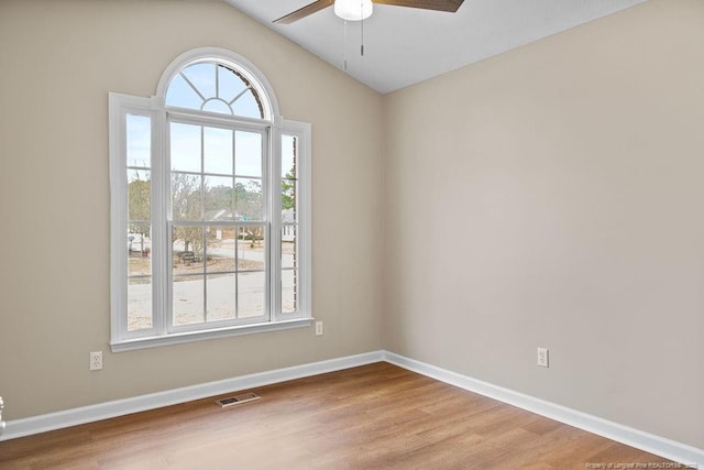 spare room featuring a wealth of natural light, visible vents, and wood finished floors