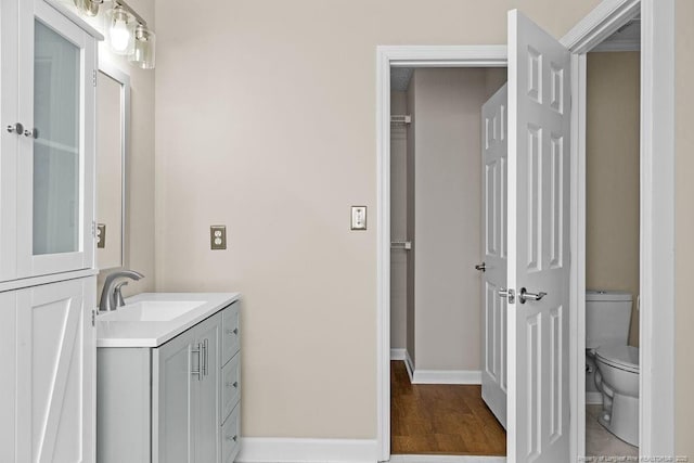 bathroom featuring baseboards, vanity, toilet, and wood finished floors