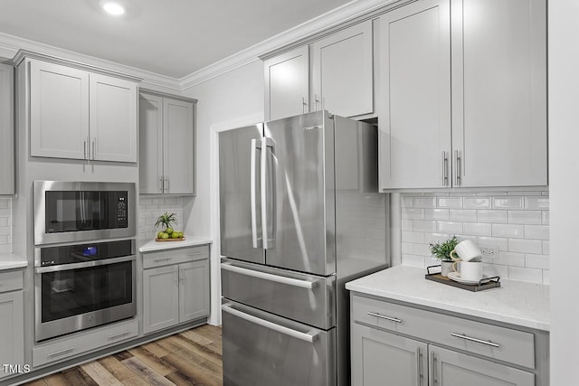 kitchen featuring tasteful backsplash, wood finished floors, gray cabinets, stainless steel appliances, and crown molding