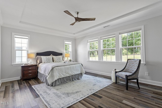 bedroom with dark wood-style floors, multiple windows, a raised ceiling, and baseboards