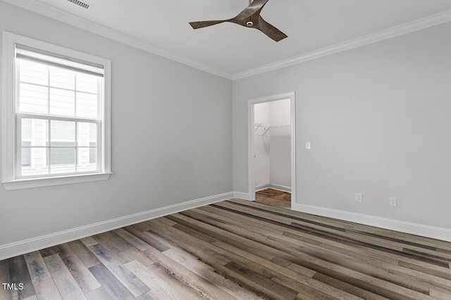 empty room featuring a ceiling fan, crown molding, baseboards, and wood finished floors