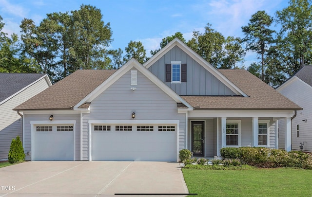 craftsman-style home with board and batten siding, a porch, a front lawn, an attached garage, and driveway
