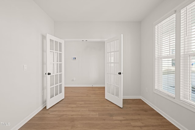 spare room featuring baseboards, wood finished floors, and french doors