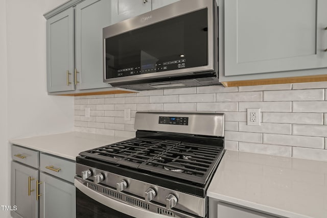 kitchen featuring appliances with stainless steel finishes, light countertops, backsplash, and gray cabinetry