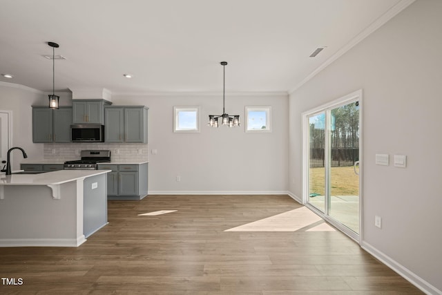 kitchen featuring stainless steel appliances, gray cabinets, light countertops, decorative backsplash, and a sink