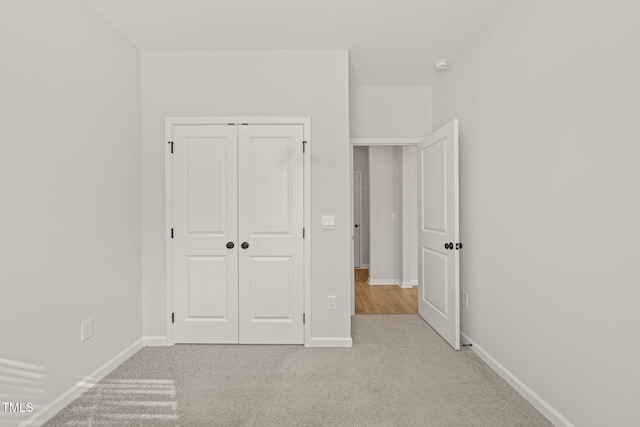 unfurnished bedroom featuring carpet, baseboards, and a closet