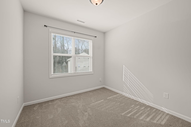 empty room with carpet, visible vents, and baseboards