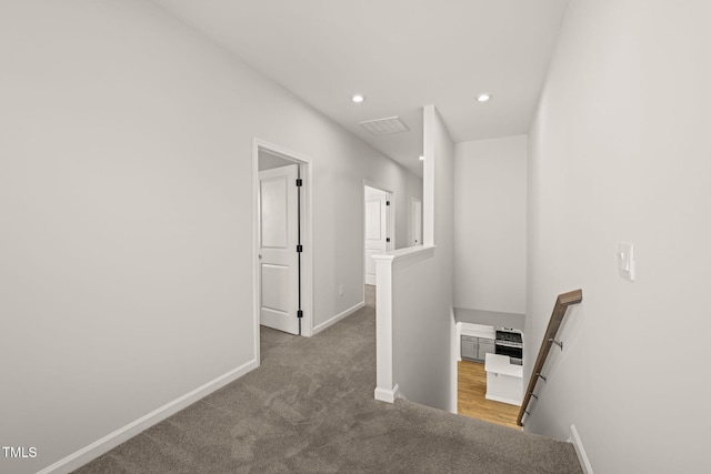 corridor with carpet, baseboards, an upstairs landing, and recessed lighting