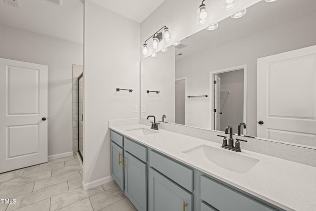 bathroom with a stall shower, a sink, baseboards, and double vanity