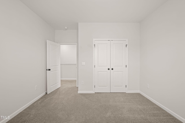 unfurnished bedroom with a closet, carpet flooring, and baseboards