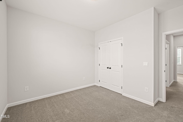 unfurnished bedroom with carpet floors, a closet, and baseboards