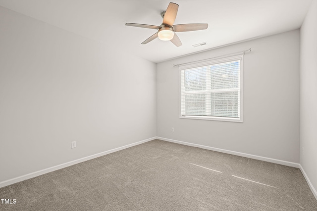 carpeted spare room with ceiling fan, visible vents, and baseboards