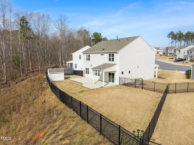 back of property featuring an outbuilding, roof with shingles, a yard, a patio, and a fenced backyard