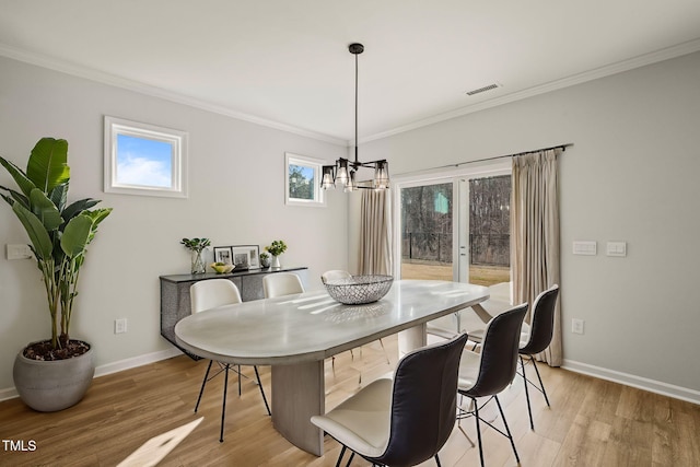 dining room with light wood-type flooring, visible vents, and ornamental molding